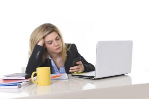 bored looking woman at work, scrolling on phone
